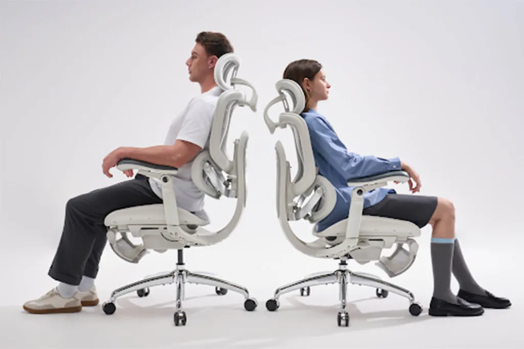 A man and a woman sitting back-to-back in two identical white ergonomic office chairs.