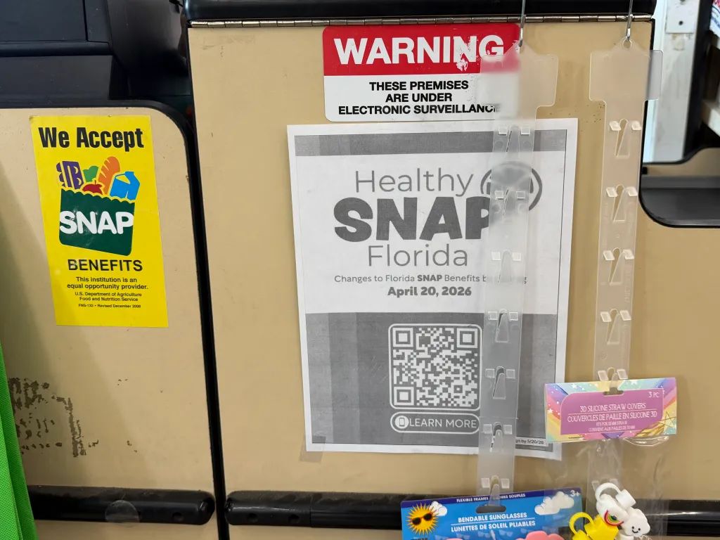 A notice of new Healthy SNAP Florida changes is posted near a store's cashier.