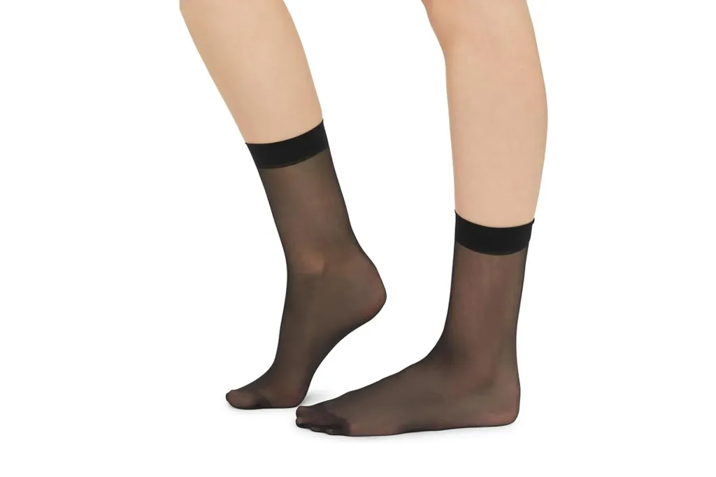 A person's legs and feet wearing sheer black ankle socks.