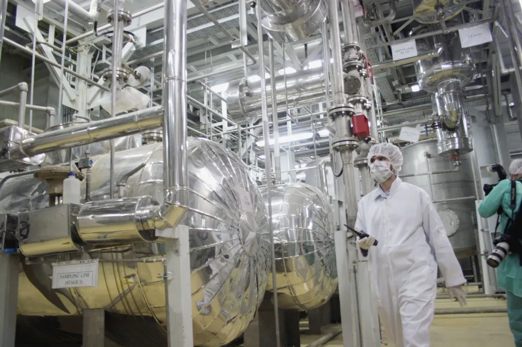 A worker in a protective suit and mask walks through a uranium conversion facility.