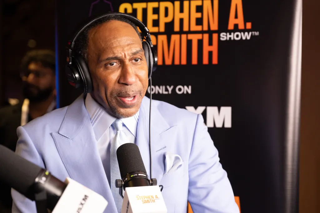 Stephen A. Smith speaking at a microphone with headphones on, in front of a "Stephen A. Smith Show" banner.