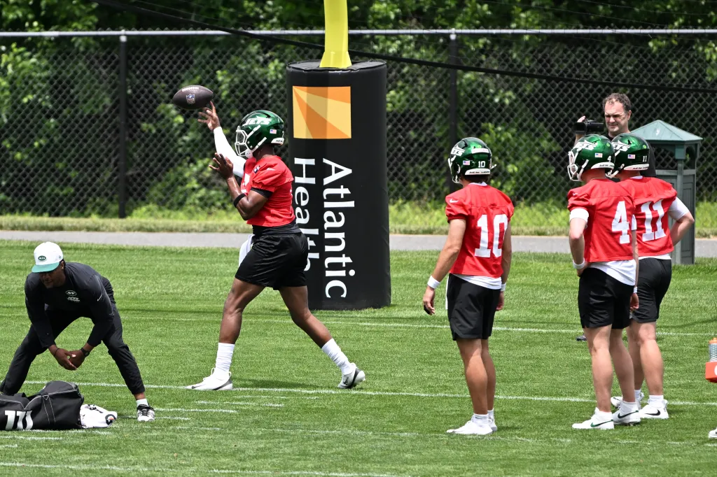Jets quarterback Geno Smith throws while Cade Klubnik, Brady Cook, and Bailey Zappe observe during OTAs.