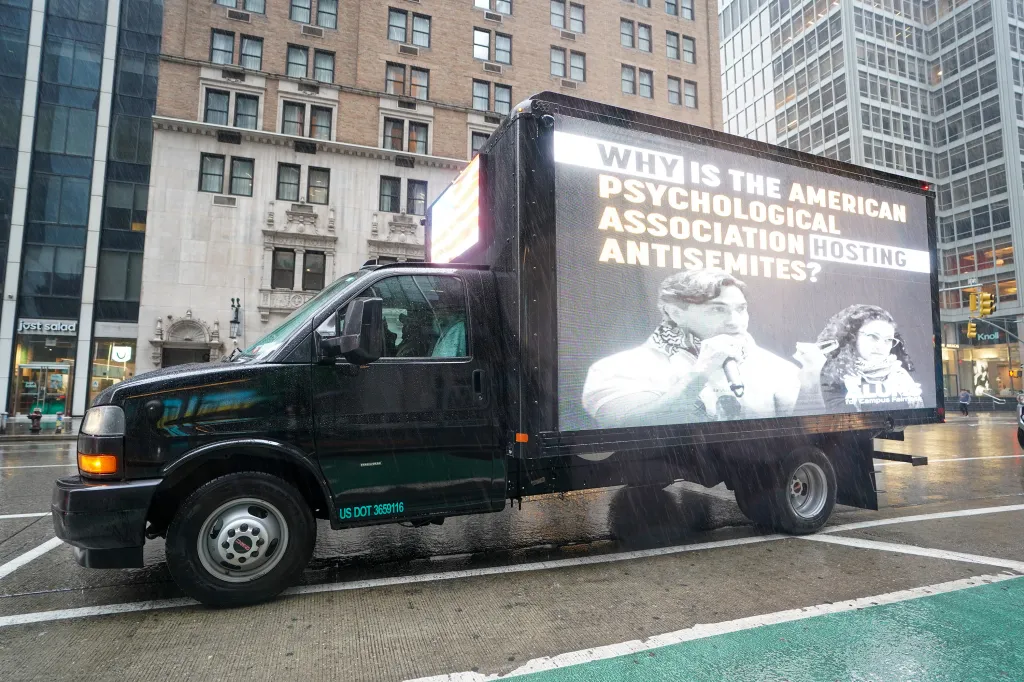 A truck with a billboard questioning why the American Psychological Association is hosting antisemites.