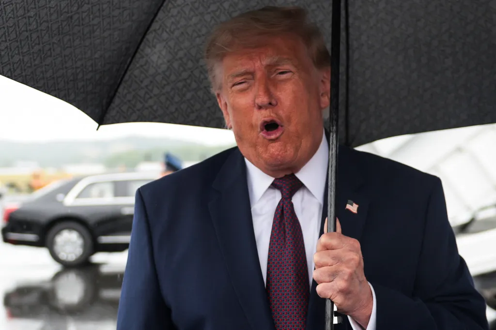 Donald Trump speaking to media at Reading Regional Airport, holding an umbrella.