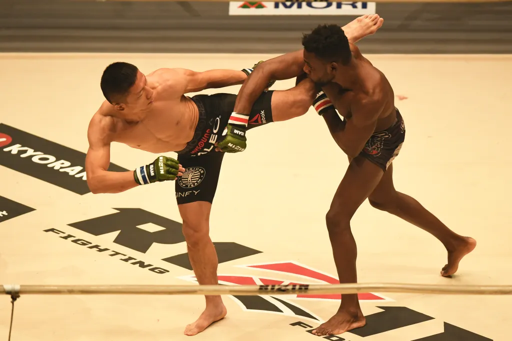 Two male RIZIN MMA fighters mid-kick during the 2017 Final Round.