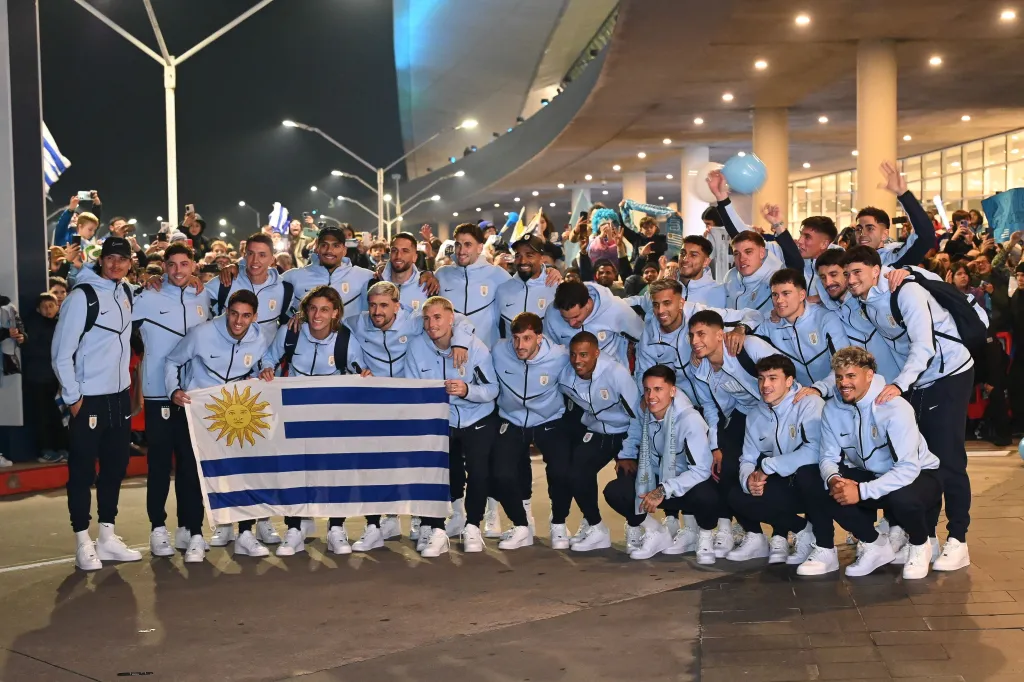 The Uruguayan national soccer team poses with their country's flag at Montevideo airport before departing for the 2026 FIFA World Cup.