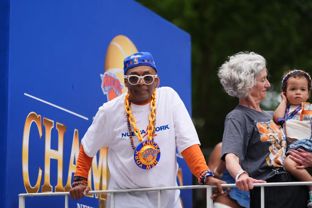 Spike Lee in a Knicks hat and chains on a parade float for the NBA Finals victory.