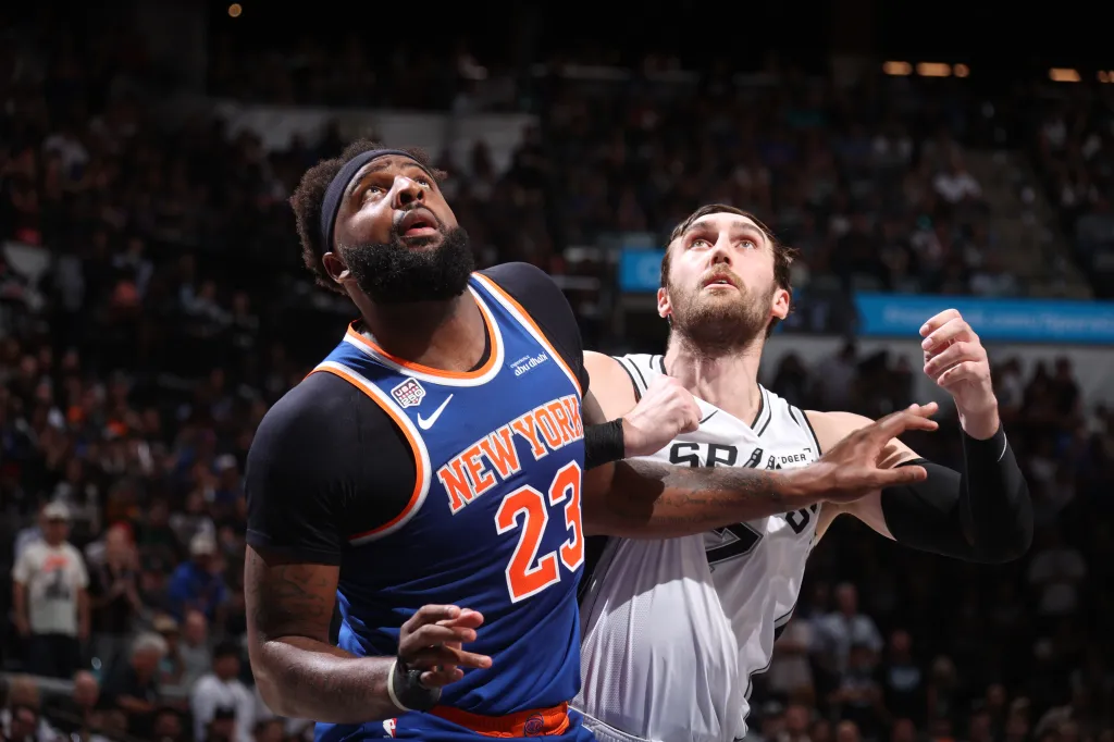 Mitchell Robinson of the New York Knicks boxing out Luke Kornet of the San Antonio Spurs during an NBA game.