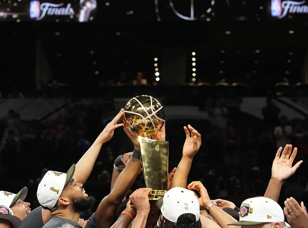 New York Knicks players raising the Larry O'Brien Championship Trophy.