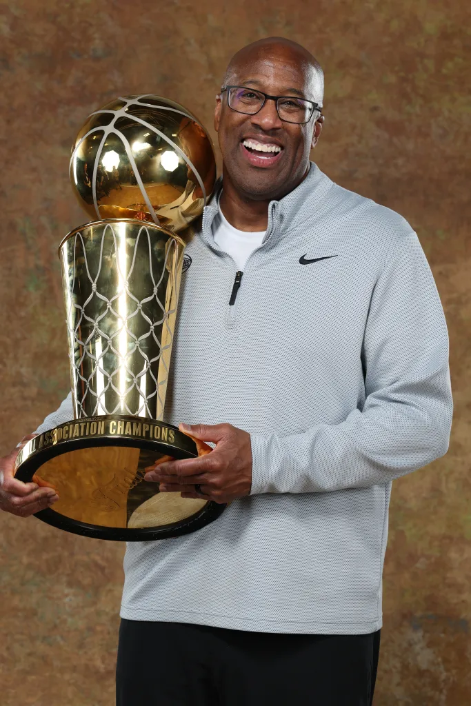 New York Knicks Head Coach Mike Brown poses with the NBA Finals trophy.