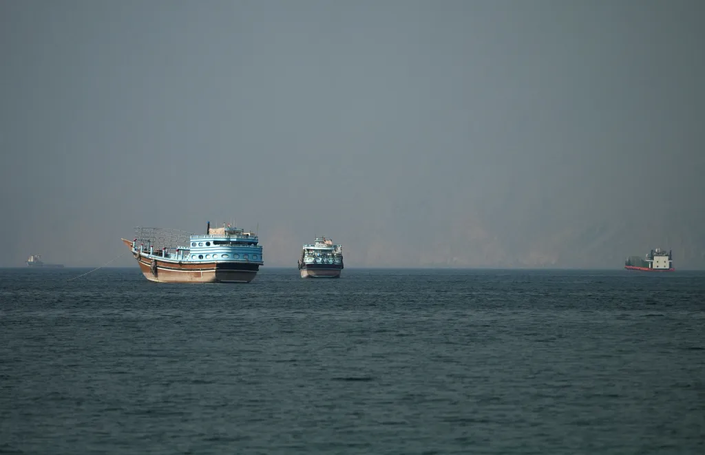Several vessels on the water at the Strait of Hormuz, with faint land in the background.