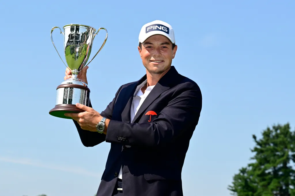 Golfer Viktor Hovland holding the Travelers Championship trophy.