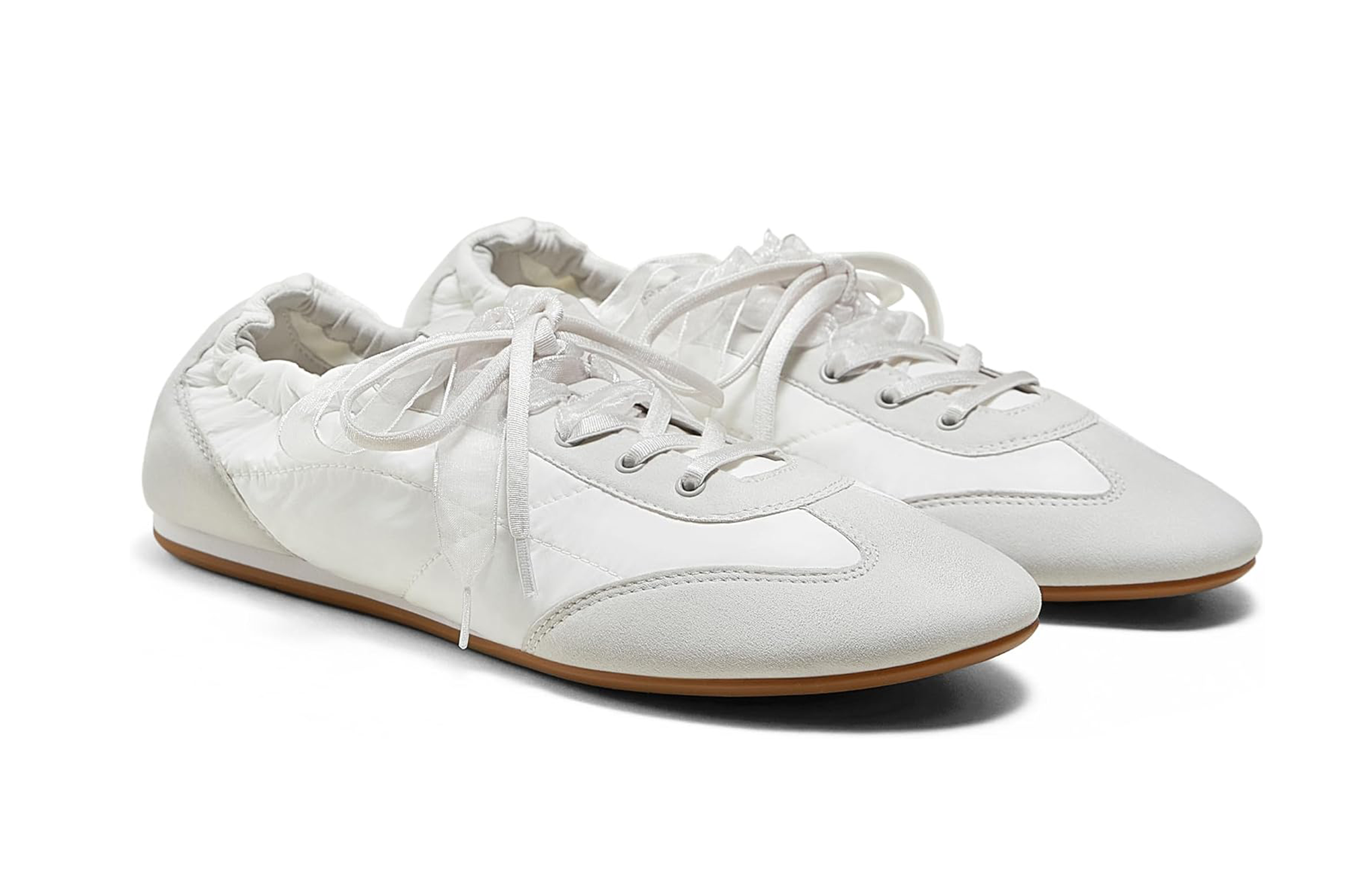 A pair of white sneakers with textured fabric, suede toe caps, and gum soles.