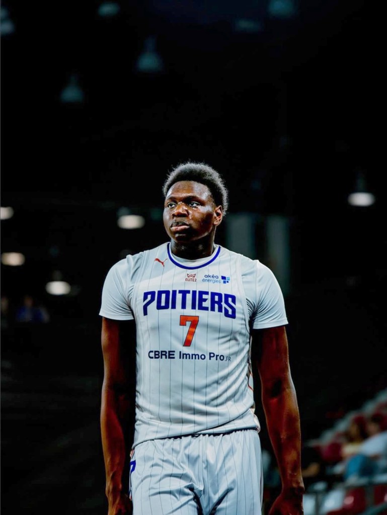Narcisse Ngoy in a white basketball jersey with "Poitiers" and "7" on it.