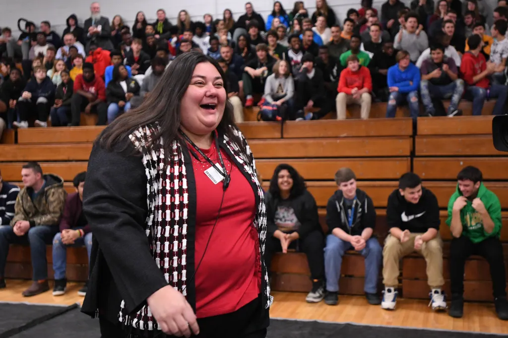 Meghan LeFevers smiling as she walks past a crowd of cheering students.