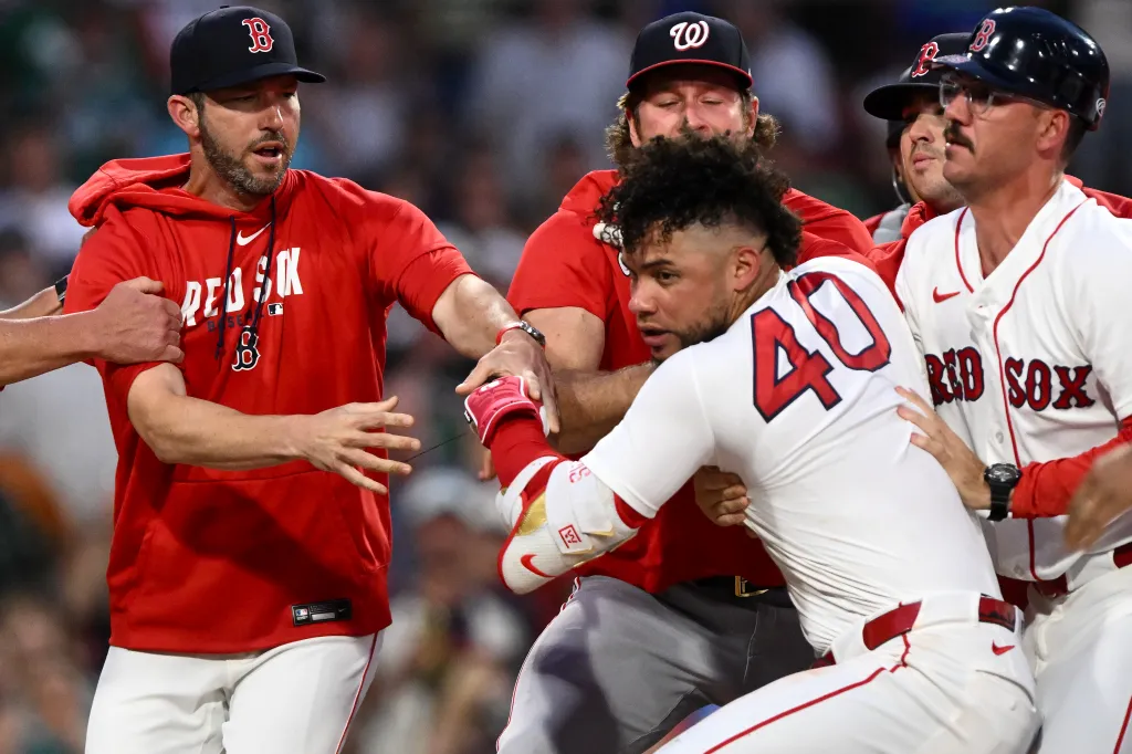 Baseball players Chad Tracy of the Washington Nationals and Willson Contreras of the Boston Red Sox are held back by teammates during an altercation.