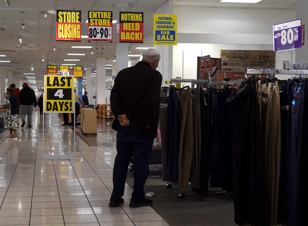 A JCPenney store during its closing sale, with a man browsing clothes.