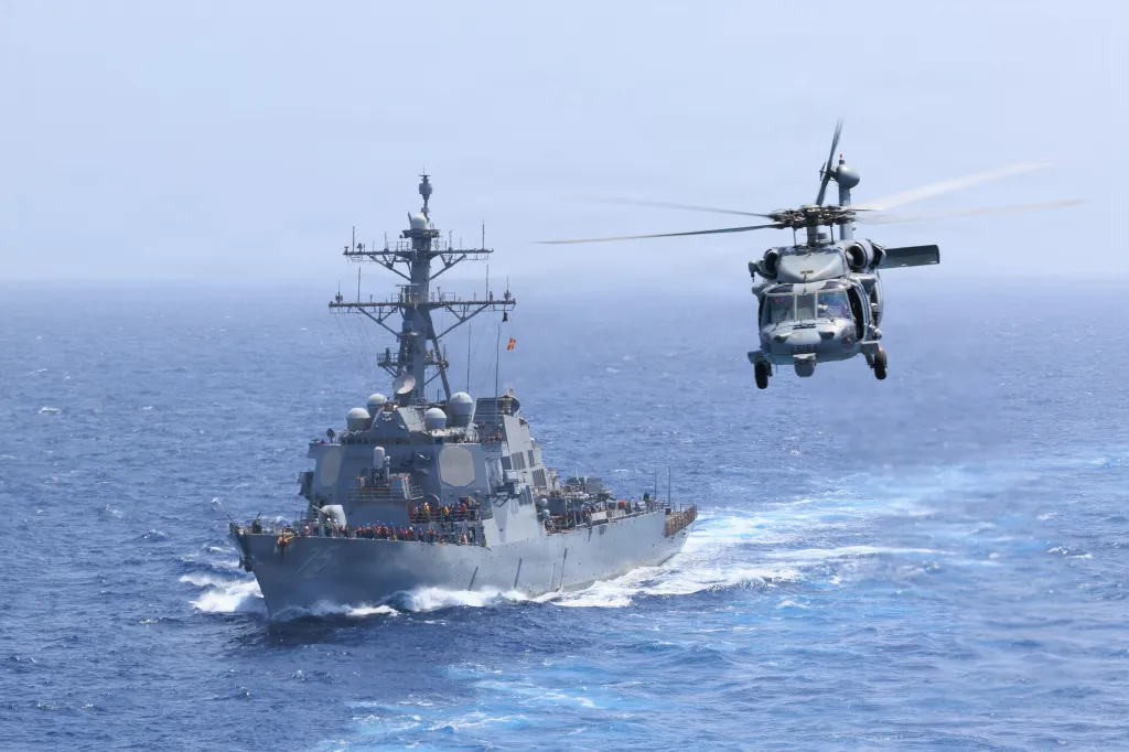 USS Donald Cook and an MH-60S Sea Hawk helicopter on the open ocean.
