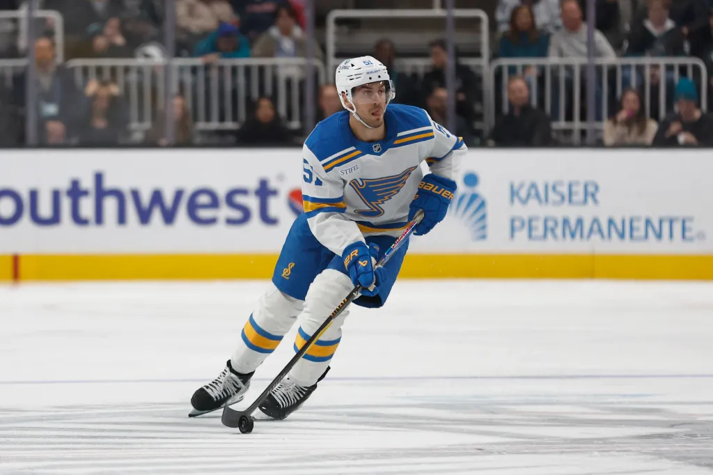 St. Louis Blues player skating on ice during a game against the San Jose Sharks.
