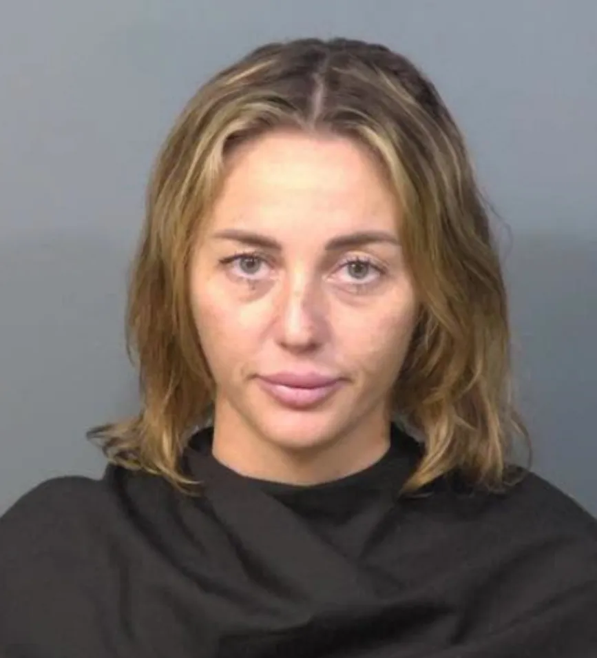 Mugshot of a woman with blonde hair, green eyes, and pink lips.
