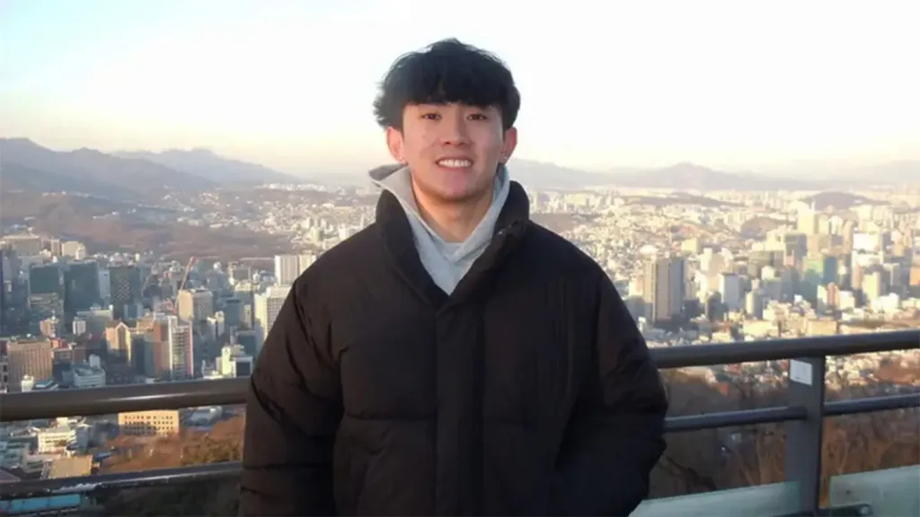 Kenny Truong, a Wichita State University student, smiles in front of a city skyline.