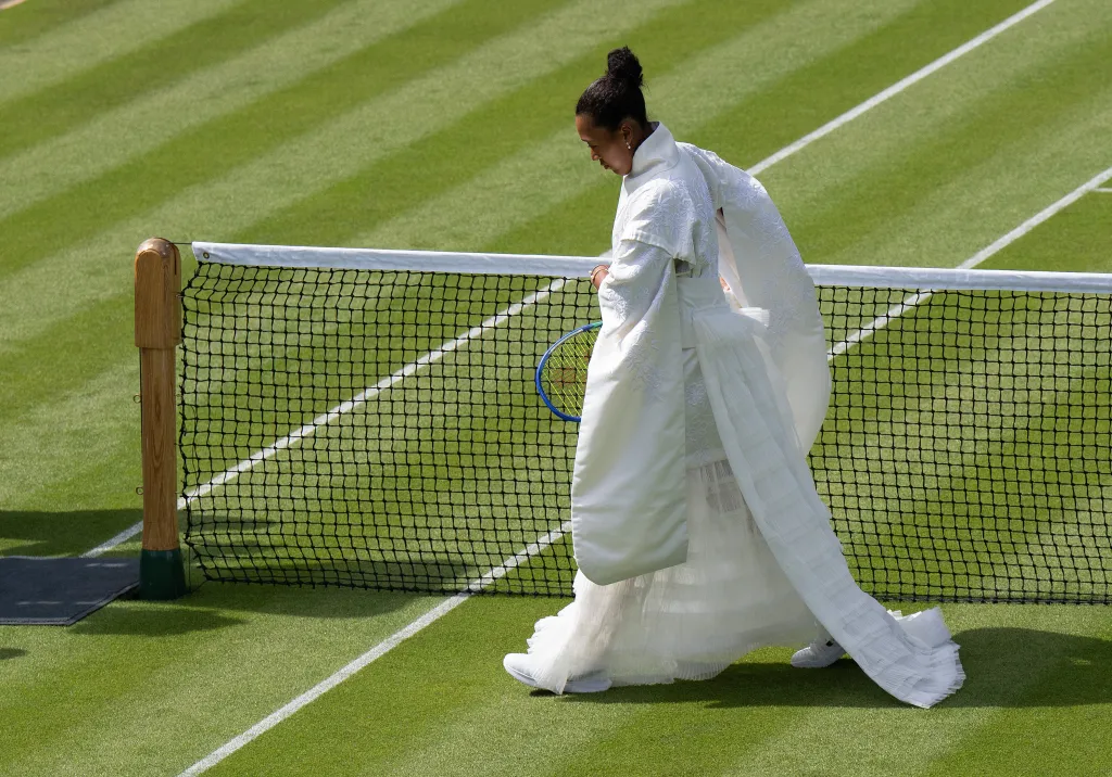 Naomi Osaka in a Japanese-inspired ceremonial dress by the tennis net at Wimbledon.